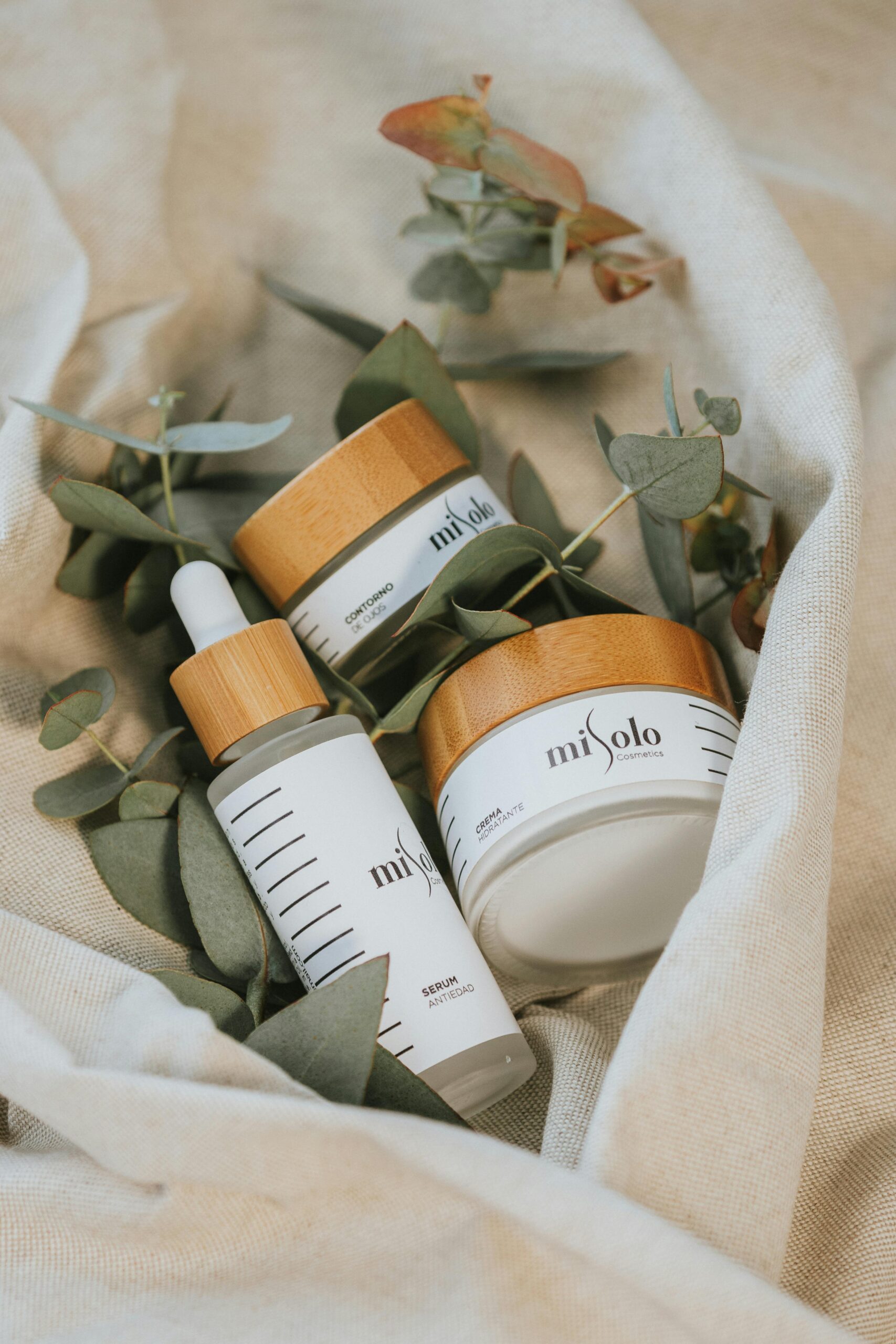 Home Natural cosmetic products with eucalyptus leaves on linen fabric for skincare routine.
